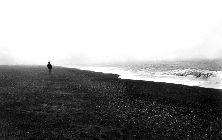 Black & white photograph. On the bleak beach