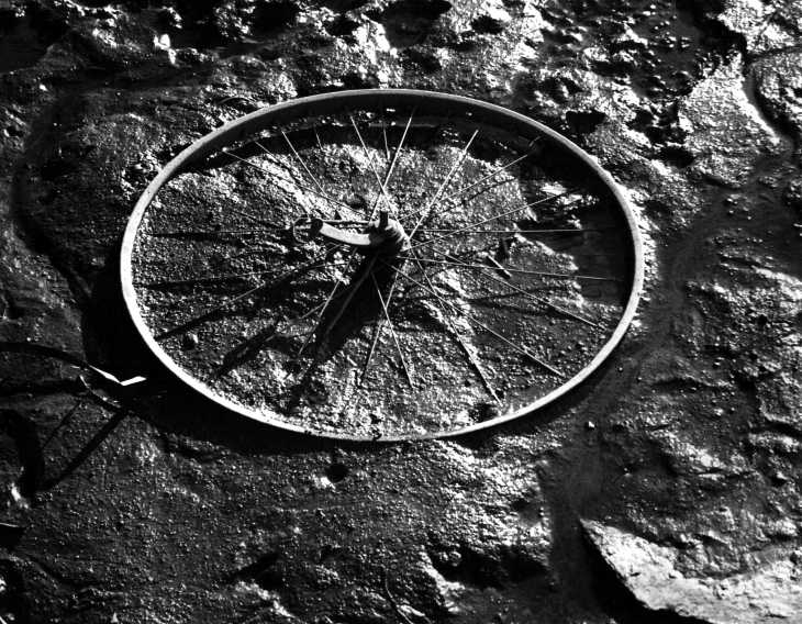 Black & white photograph. Wheel in mud
