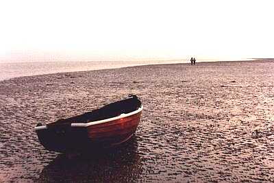 Rowing boat and distant couple, Worthing beach, Sussex